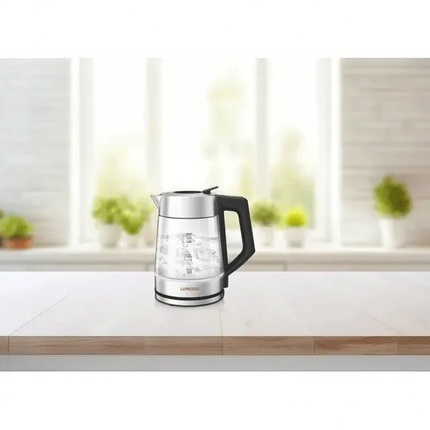 Glass electric kettle on a kitchen counter with a blurred window background