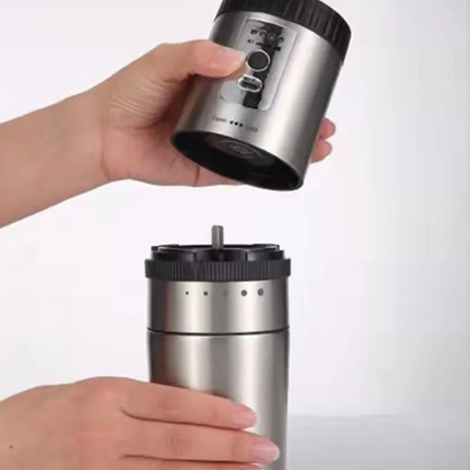 Two hands holding a silver and black coffee grinder against a white background