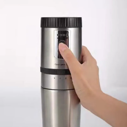 Hand holding a stainless steel and black coffee grinder on a white background