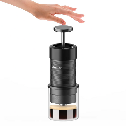 La Presso coffee press on a white background with a hand reaching towards it.
