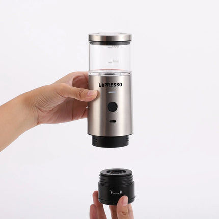 Hand holding a Lèpresso portable coffee maker on a white background