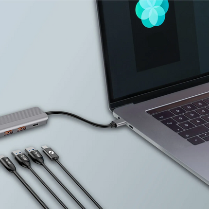 Laptop with a USB hub and multiple cables on a light gray background
