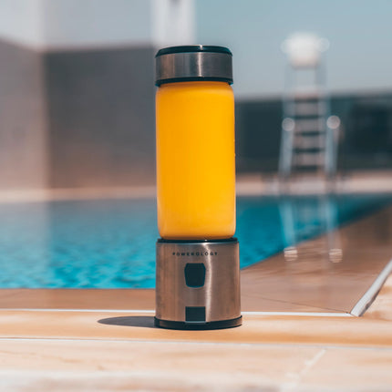 Yellow and silver blender on a wooden deck by a pool