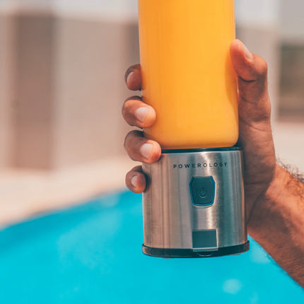 Hand holding a yellow and silver power bank by a pool