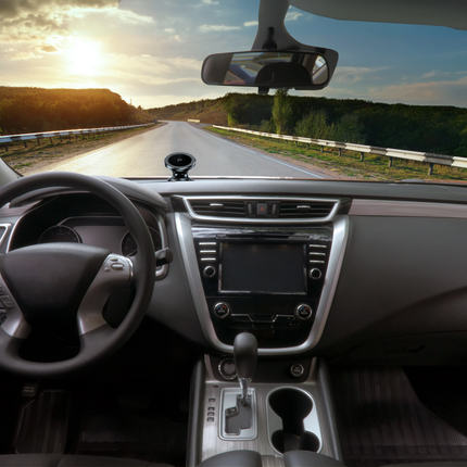 Car interior with a view of a road ahead during sunset.